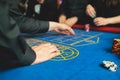 Vibrant casino table with roulette in motion, with casino chips, tokens, the hand of croupier, dollar bill money and a group of Royalty Free Stock Photo