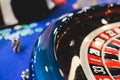 Vibrant casino table with roulette in motion, with casino chips, tokens, the hand of croupier, dollar money and a group of Royalty Free Stock Photo