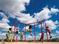 Friends swinging on colorful swings under blue sky