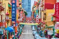 Vibrant Chinatown view of crowded sidewalks and row of parked cars with hanging lanterns and signs Royalty Free Stock Photo