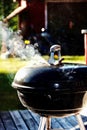 Vibrant, close-up shot of a charcoal grill sitting on a wooden deck in the sunshine