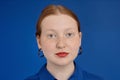 Vibrant closeup red haired young woman looking at camera on blue