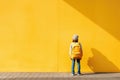 Yellow wall background, back to primary school boy, back to school. Generative ai Royalty Free Stock Photo