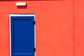 Vibrant colorful paint. Blue painted door on red building. Royalty Free Stock Photo