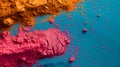 Vibrant colorful piles of orange and pink pigment powders gather in horizontal on blue background at the left side of image.