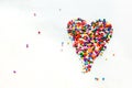 Colorful sugary sprinkles heart shape lay on white texture background. Royalty Free Stock Photo