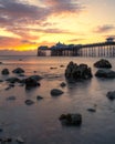 Vibrant colorful sunrise over the rugged rocky coastline with Llandudno Pier in the background Royalty Free Stock Photo