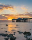 Vibrant colorful sunrise over the rugged rocky coastline with Llandudno Pier in the background - North Wales Royalty Free Stock Photo