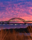 Vibrant colorful sunset sky behind a long steel tied arch bridge. Fire Island New York