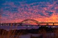 Vibrant colorful sunset sky behind a long steel tied arch bridge. Fire Island New York