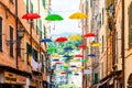 Vibrant colorful umbrellas hanging on cables fixed high on building facades Royalty Free Stock Photo