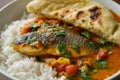 A vibrant dish showcases fish curry featuring an array of spices, accompanied by fluffy steamed rice and soft naan bread Royalty Free Stock Photo