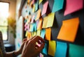 Colorful sticky notes on a black board with hands arranging them Royalty Free Stock Photo