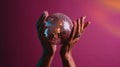 Hand holding disco ball on pink background