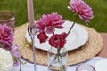 Vibrant floral arrangement and tall candles on sunny garden table. Spring wedding and garden party settings. Royalty Free Stock Photo