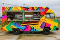 A vibrant food truck with a variety of colors is seen parked in a spacious parking lot, Maximalist design of a food truck with