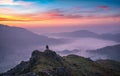 Vibrant gorgeous dawn sunrise clouds above a misty valley in the beautiful Lake District with lone hiker
