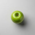 A vibrant green apple rests against a light gray background. Its smooth, glossy surfac Royalty Free Stock Photo