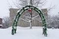 Vibrant green arch decorated with colorful garlands, ornaments and balls in a snowy park Royalty Free Stock Photo