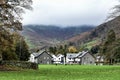 Vibrant green field with buildings and majestic mountains in the distance