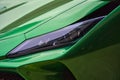 the front end of a green sports car driving on the street