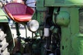 Vibrant green tractor with a red seat in a street setting