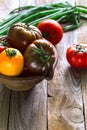 Vertical various tomatoes in clay bowl in contr light decorated with green fresh onion.