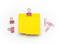 Yellow Sticky Note with Pink Binder Clips and Paperclips on White Background Royalty Free Stock Photo