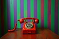 Vintage red rotary telephone on colorful striped background