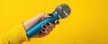 The vibrant microphone held in a stylish hand against a bright yellow background..AI generated image Royalty Free Stock Photo