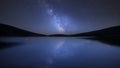 Vibrant Milky Way composite image over landscape of calm lake with reflections