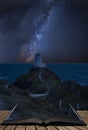 Vibrant Milky Way composite image over landscape of lighthouse on end of headland with beautiful sky coming out of pages in Royalty Free Stock Photo