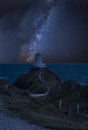 Vibrant Milky Way composite image over landscape of lighthouse on end of headland with beautiful sky