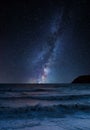 Vibrant Milky Way composite image over landscape of long exposure waves in ocean