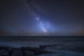 Vibrant Milky Way composite image over landscape of pier at sea