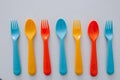 Vibrant multicolored forks, kives and spoons white background