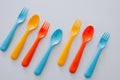 Vibrant multicolored forks, kives and spoons white background