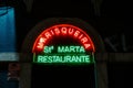 Vibrant neon sign illuminates the entrance of a cozy restaurant of St Marta