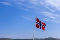 A vibrant Norwegian flag unfurling against a cerulean sky on a sunlit summer day Royalty Free Stock Photo