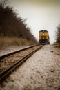 Vibrant orange passenger train traveling along a scenic countryside train track