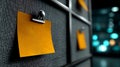 Vibrant orange sticky note with clip on dark textured board, copy space, soft bokeh lights, cinematic detail. Royalty Free Stock Photo