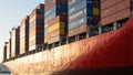 Vibrant painted container ship hull with colorful cargo containers casting long shadows Royalty Free Stock Photo