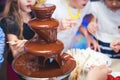 Vibrant Picture of Chocolate Fountain Fontain on childen kids birthday party with a kids playing around and marshmallows and fruit Royalty Free Stock Photo