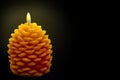 A vibrant pine candle with naturally formed structure lit or burning fire and spreading light isolated against dark black Royalty Free Stock Photo