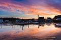 Vibrant pink and orange pastel colored clouds during a sunset. Coastal village and fishing pier reflected in the water.