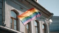 Waving pride flag outside a building with windows, showcasing vibrant colors and Royalty Free Stock Photo
