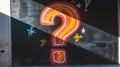 Vibrant question mark graffiti on a black wall, illuminated by slanting sunlight. Royalty Free Stock Photo