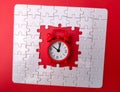 a red alarm clock is sitting in a puzzle piece shaped as a square