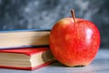 A vibrant red apple rests gracefully on top of a stack of books, showcasing the perfect blend of knowledge and Royalty Free Stock Photo