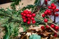 Vibrant red artificial berries atop mess of green spruce branches on brown background. Traditional Christmas red and green decor Royalty Free Stock Photo